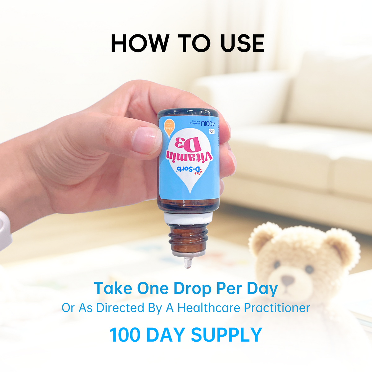 A hand holds a small amber bottle labeled Vitamin D3 Soft in front of a blurred living room background with a teddy bear. Text reads 'HOW TO USE' and 'Take One Drop Per Day Or As Directed By A Healthcare Practitioner 100 DAY SUPPLY'.